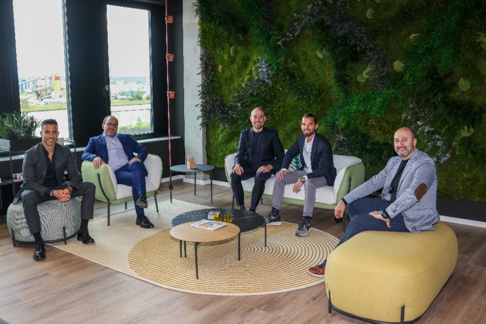 Abbildung: Vince Berbegal, Fernando Seva, Luis Araujo, Daniel Weber und Jose Garcia sitzen im Halbkreis vor einer grün bewachsenen Wand.