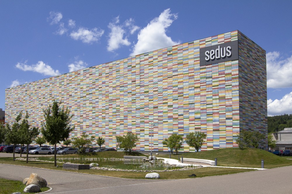 Abbildung: Bunt gekacheltes, rechteckiges Gebäude mit der Aufschrift "Sedus".